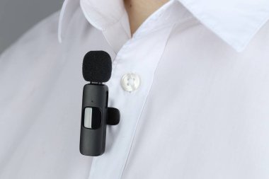 Gömleğine mikrofon takmış bir adam, yakın plan.