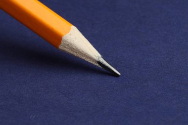 Mavi arkaplanda keskin bir grafit kalem, yakın plan.