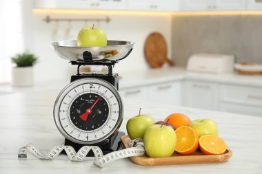 Meyveli mutfak pulları ve kapalı alandaki hafif mermer masada mezura.