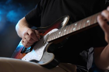 Karanlık arka planda gitar çalan adam dumanlı, yakın plan