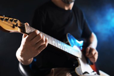 Karanlık arka planda gitar çalan adam dumanlı, eline odaklan