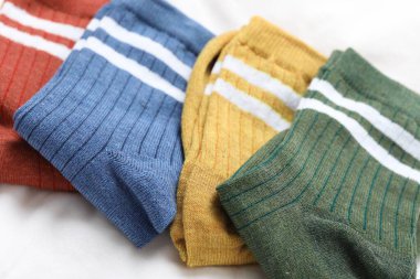 Beyaz battaniyede farklı yumuşak çoraplar, yakın çekim.