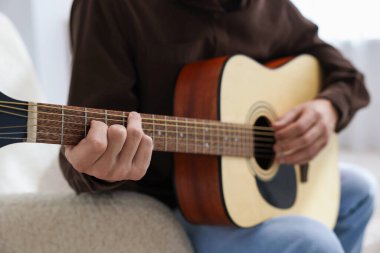 Sandalyede gitar çalan adam, yakın plan.
