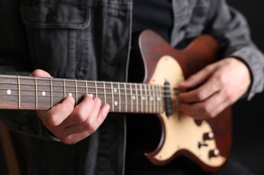 Siyah arkaplanda gitar çalan adam, yakın plan