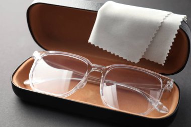 Gri arka planda şık gözlüklü ve temizlik bezli çanta, yakın plan.