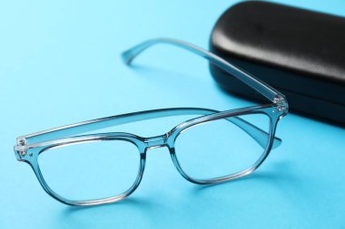 Açık mavi arka planda şık gözlüklü çanta, yakın plan