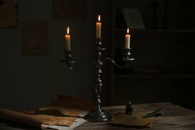 Mumları şamdanla yakmak, eski kağıtlar, mürekkep hokkası ve tüy kapalı masa üzerinde.