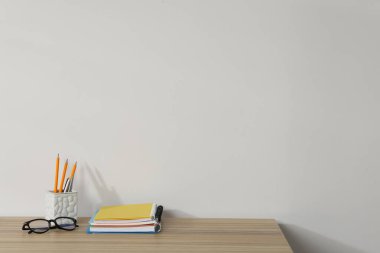 Ahşap ofis masasında farklı kırtasiye ve gözlük beyaz arkaplan, metin için yer