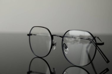 Gri ayna yüzeyinde şık gözlükler, yakın plan.