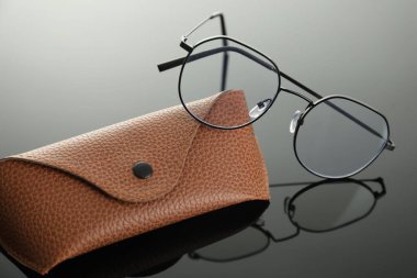 Gri ayna yüzeyinde şık gözlükler ve çanta, yakın plan.