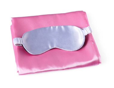 Beyaz arka planda ipek çarşaflar ve uyku maskesi.