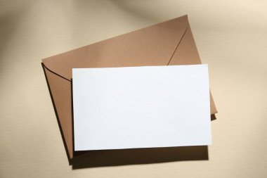 Bej arka planda boş tebrik kartı ve kağıt zarf, üst görünüm