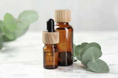 Gerekli yağ ve okaliptüs şişeleri beyaz mermer masa üzerinde, yakın çekim