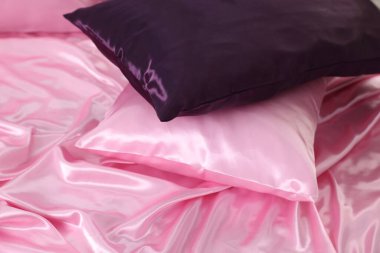 Lüks pembe ipek çarşaflar ve yastıklar yatakta, yakın plan.