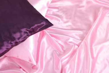 Lüks pembe ipek çarşaflar ve yastıklar yatağın üstünde.