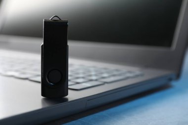 USB flash disk ve dizüstü bilgisayar mavi masada, yakın plan.
