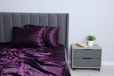 Lüks ipek çarşaflar yatağın üzerinde ve komodinin üzerinde.