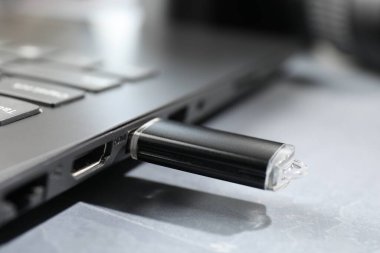 Gri desenli masadaki dizüstü bilgisayara bağlı flaş bellek, yakın plan.