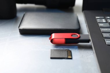 Dizüstü bilgisayara, SD hafıza kartına ve gri masadaki harici sabit diske bağlı flaş bellek.