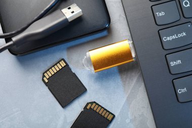 Dizüstü bilgisayara, SD hafıza kartlarına ve gri desenli tablodaki harici sabit diske bağlı flaş bellek, düz konum