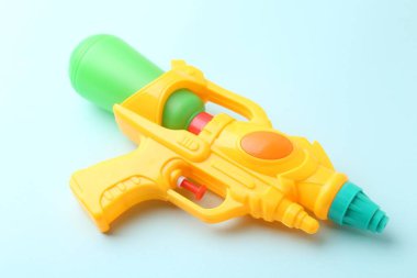 Açık mavi arkaplanda parlak plastik su tabancası, yakın plan.