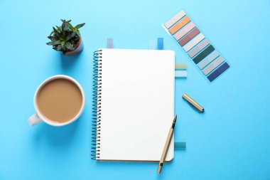Açık boş defter, diğer kırtasiye malzemeleri, açık mavi zemin üzerinde kahve ve çiçek dekoru, düz uzanma