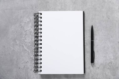 Kalem ve açık defter gri masada, düz yatıyordu.