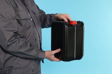 Açık mavi arka planda plastik kutu tutan adam, yakın plan.