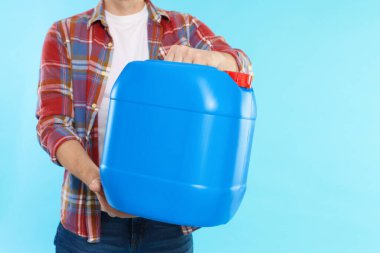 Açık mavi arka planda plastik kutu tutan adam, yakın plan. Metin için boşluk
