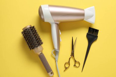 Sarı arka planda farklı saç şekillendirme araçları, düz yatış