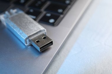 Flaş bellek ve laptop açık gri masada, yakın plan. Metin için boşluk