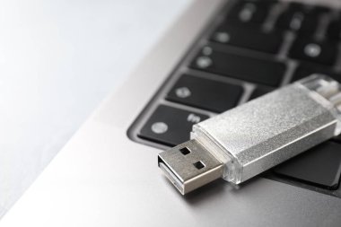 Flaş bellek ve laptop açık gri masada, yakın plan.