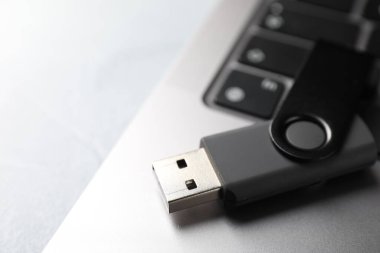Flaş bellek ve laptop açık gri masada, yakın plan.