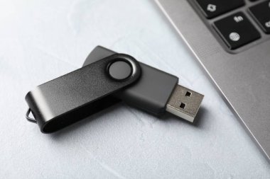 Flaş bellek ve laptop açık gri masada, yakın plan.