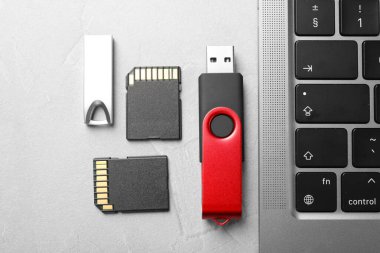 Flaş bellekler, SD hafıza kartları ve dizüstü bilgisayarlar açık gri tabloda, düz konumda