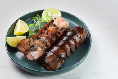 Çiğ ıstakoz kuyruğu, kireç ve mikro yeşiller beyaz mermer masada, yakın plan.