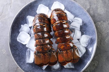 Çiğ ıstakoz kuyruğu ve gri masa, üst manzara.