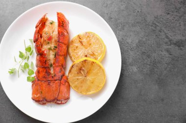 Lezzetli ıstakoz kuyruğu, mikro yeşillikler ve gri desenli masa üzerindeki limon dilimleri, üst manzara. Metin için boşluk