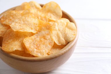 Lezzetli patates cipsleri beyaz ahşap masada, yakın plan. Metin için boşluk