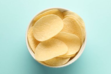 Açık mavi arka planda leziz patates cipsi, üst manzara.