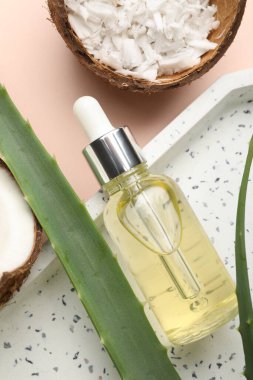Saç tedavisi. Kozmetik ürünler, hindistan cevizi, tereyağı talaşı ve bej arka planda aloe yaprakları, düz yatış
