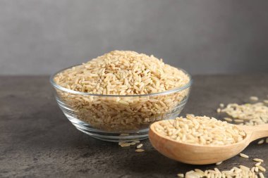 Kahverengi pirinç kasede ve kaşık gri masada, yakın plan.