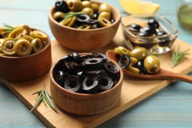 Farklı lezzetli marine edilmiş zeytin halkaları, tüm olanlar ve biberiye açık mavi ahşap masa, yakın çekim