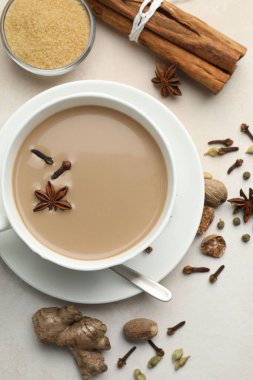 Aromatik Masala çayı bardakta, baharatlar ve kahverengi şeker açık gri masada, düz yerde.