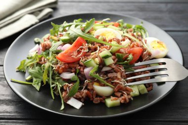Siyah ahşap masada kahverengi pirinçli leziz salata, yakın plan.