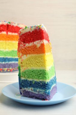Lezzetli bir parça gökkuşağı pastası beyaz masada, yakın plan.