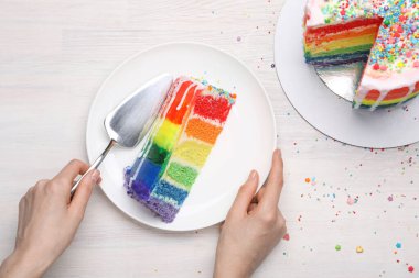 Lezzetli gökkuşağı pastası ve spatulası olan kadın açık ahşap masada, üst tarafta.
