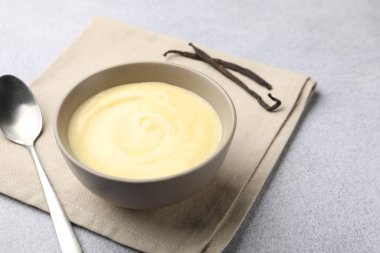 Kasede vanilyalı puding, kapsüller ve kaşıklar açık gri masada, yakın plan. Metin için boşluk