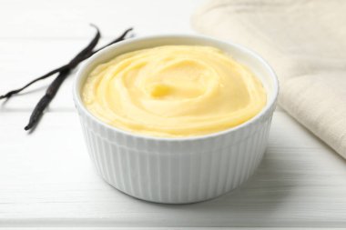 Lezzetli vanilyalı puding ve kapsüller beyaz ahşap masada, yakın plan.