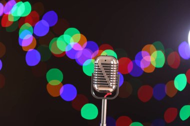 Karanlık arka planda bulanık ışıkları olan klasik mikrofon, mesaj için yer. Müzik ekipmanları